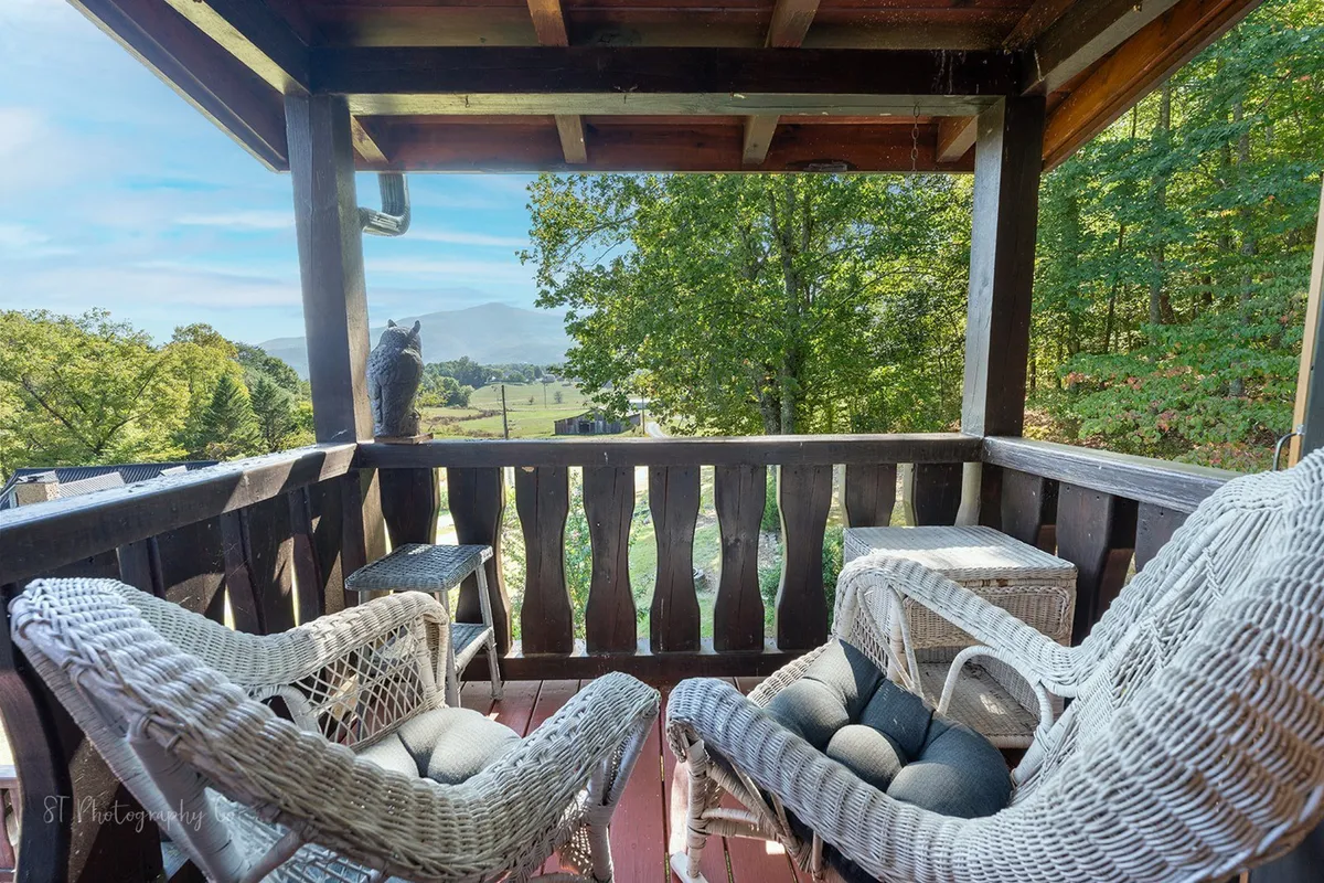 This exterior shot features woven chairs on a deck with a scenic view beyond a wooden railing, emphasizing peaceful outdoor living and panoramic Smoky Mountain vistas. The image evokes sunrise moments or evening gatherings while surrounded by nature.