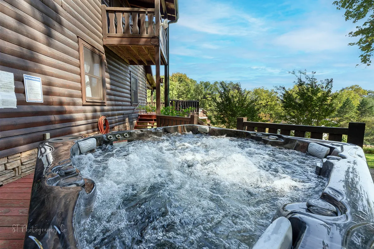 This image captures a tranquil outdoor hot tub on a wooden deck surrounded by trees, inviting relaxation while immersed in natural beauty. The deck setting visually connects the cabin experience to the Smoky Mountains and highlights amenities tied directly to nature.