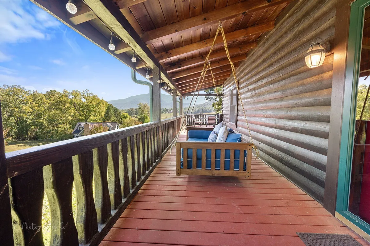 A peaceful covered porch with a swinging seat, decorative lights, wooden railing, and sweeping mountain views. The setting is ideal for evening relaxation, storytelling, or stargazing as a family.
